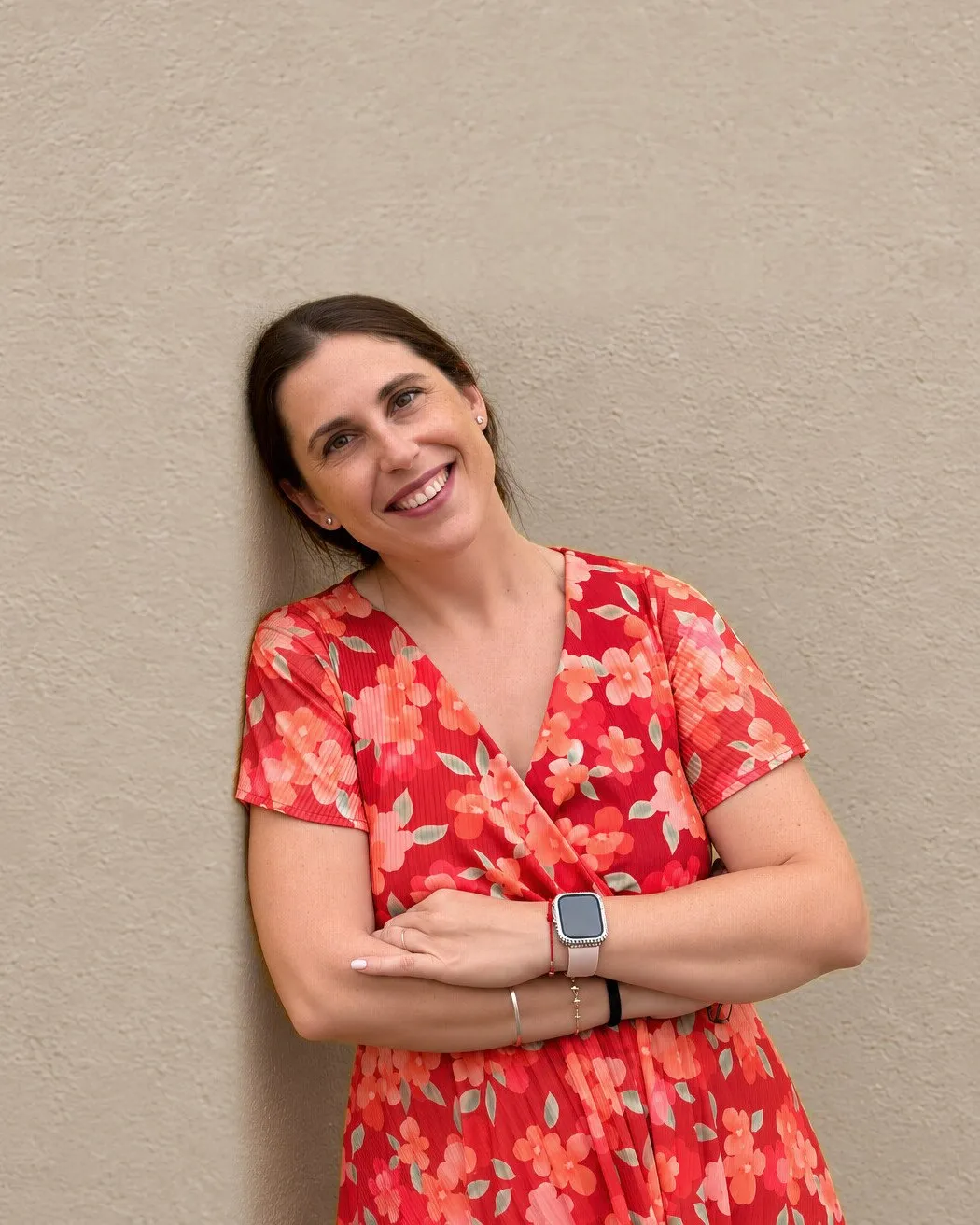 Andrea Arcusa leaning on a wall, smiling